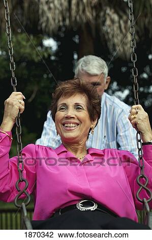 Stock Image - fort lauderdale, florida, united states of america; a man pushing a woman on the swing. Fotosearch