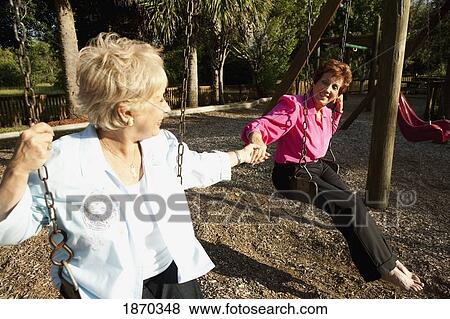 Stock Photo - fort lauderdale, florida, united states of america; two women on the swings. Fotosearch