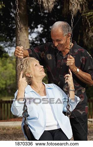 Stock Photograph - fort lauderdale, florida, united states of america; a married couple with the woman sitting on a swing. Fotosearch