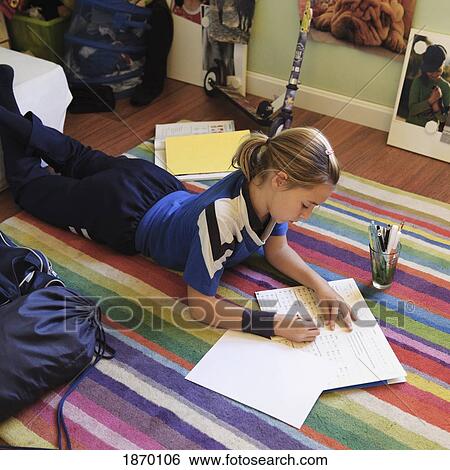 Stock Photograph - girl doing homework on the floor. Fotosearch