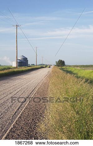 Stock Photo - gravel road with silos in the distance, south of calgary, alberta, canada. Fotosearch