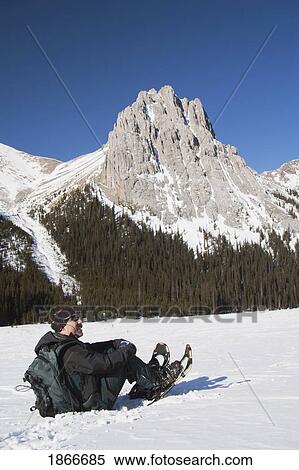 Man in snowshoes sitting in the snow View Large Photo Image Stock Photography - Man in snowshoes sitting in the snow. Fotosearch