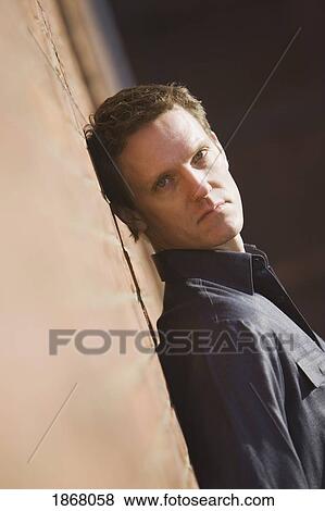 Stock Photo - man leaning against a wall. Fotosearch