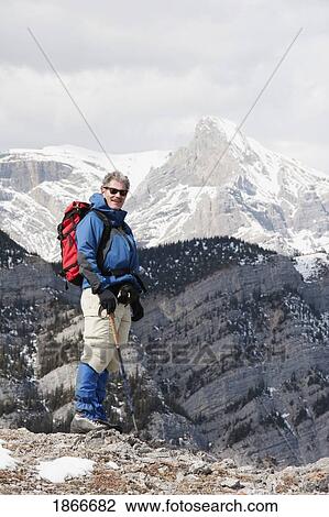 Stock Image - Man standing at the top of a mountain. Fotosearch