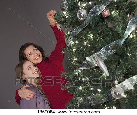 Picture - mother and daughter decorating the christmas tree. Fotosearch