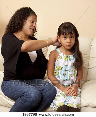Stock Photograph - mother doing her daughter's hair. Fotosearch