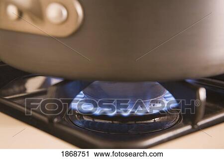 Stock Image - pot on a gas stove top with blue flame. Fotosearch