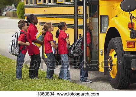 Picture - students lined up to get on the school bus. Fotosearch