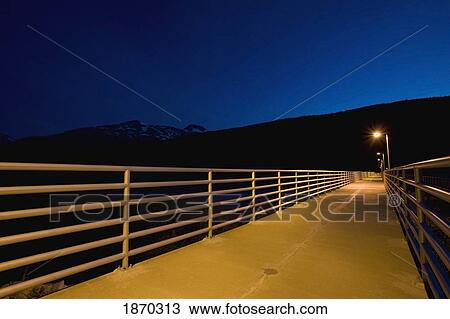Stock Image - taiya inlet, skagway, alaska, united states of america; pat moore bridge flooded with lights at night. Fotosearch