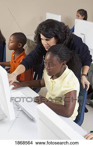 Picture - teacher helping students in computer class. Fotosearch