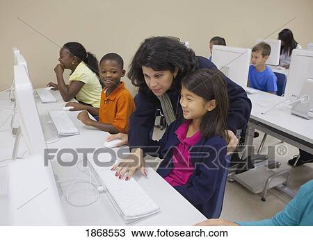 Stock Image - teacher working with students in computer class. Fotosearch