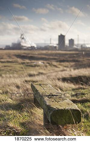 Stock Photography - teesside, england; a wooden bench in a field with an industrial area in the background. Fotosearch
