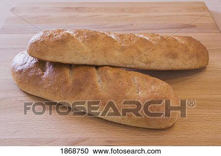 two loaves of baked bread on a cutting board View Large Photo Image Stock Image - two loaves of baked bread on a cutting board. Fotosearch
