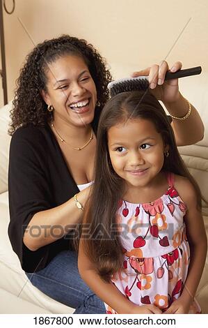 Stock Image - woman doing her daughter's hair. Fotosearch