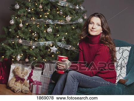 woman sitting by the christmas tree View Large Photo Image Stock Photo - woman sitting by the christmas tree. Fotosearch