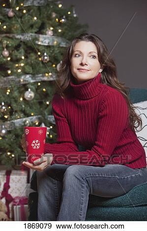 Stock Photo - woman sitting by the christmas tree. Fotosearch