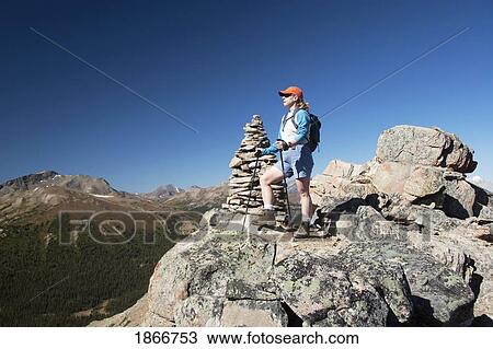 Stock Image - Woman standing on the top of a mountain. Fotosearch