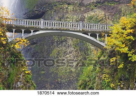 a bridge between two steep slopes with a waterfall behind it View Large Photo Image Picture - a bridge between two steep slopes with a waterfall behind it. Fotosearch