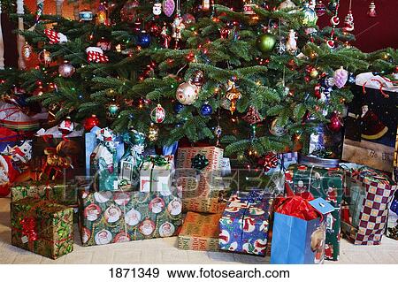 Stock Photo - a christmas tree with gifts underneath it. Fotosearch