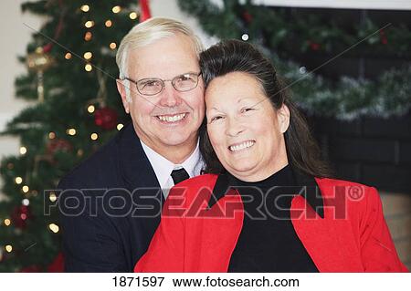 Stock Photo - a couple sitting in front of the christmas tree. Fotosearch