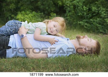 Download A father and daughter laying together on the grass Stock ...