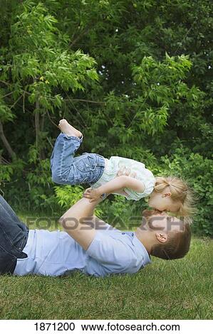 Stock Image - a father and daughter playing together on the grass. Fotosearch
