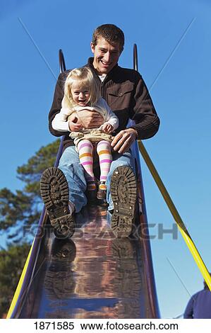 Stock Photography - a father going down the slide with his young daughter. Fotosearch