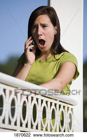Stock Image - a girl talking on her cell phone with a surprised look. Fotosearch