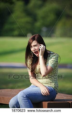 Stock Image - a girl talking on her cell phone with a surprised look. Fotosearch