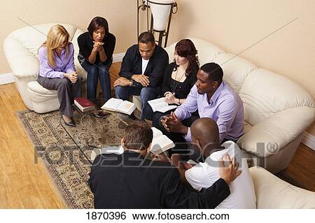 Stock Photograph - a group of adults praying with their bibles open. Fotosearch