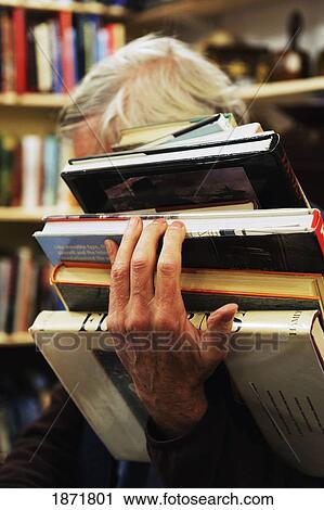 Stock Image - a man holding a pile of books. Fotosearch