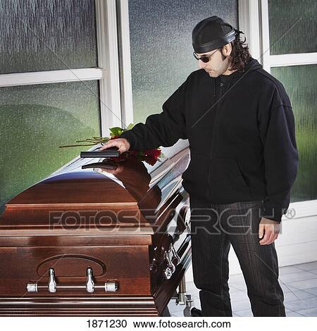 a man laying his gun on top of a coffin View Large Photo Image Stock Image - a man laying his gun on top of a coffin. Fotosearch