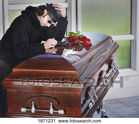 a man laying his gun on top of a coffin View Large Photo Image Stock Image - a man laying his gun on top of a coffin. Fotosearch
