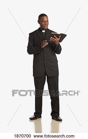 Stock Image - a man wearing a clerical collar and reading from the bible. Fotosearch