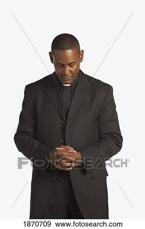Stock Photo - a man wearing a clerical collar with his head bowed in prayer. Fotosearch
