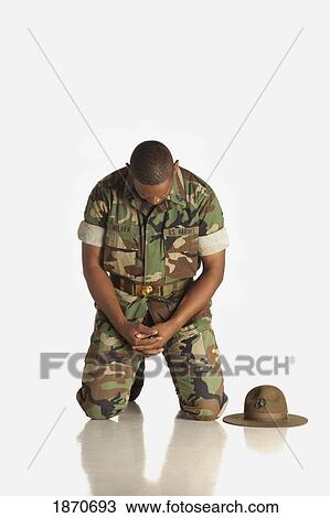 Stock Image - a military man kneeling with his head bowed in prayer. Fotosearch