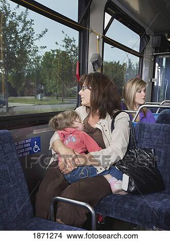 Picture - a mother holding her young daughter on the bus. Fotosearch