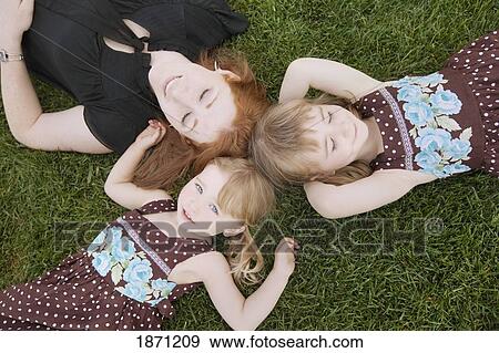 a mother laying on the grass with her two daughters View Large Photo Image Stock Photo - a mother laying on the grass with her two daughters. Fotosearch