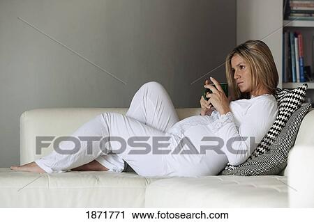 Stock Image - a pregnant woman lounging on the couch. Fotosearch