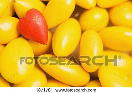 a red heart shaped candy on a pile of yellow candies View Large Photo Image Stock Image - a red heart shaped candy on a pile of yellow candies. Fotosearch