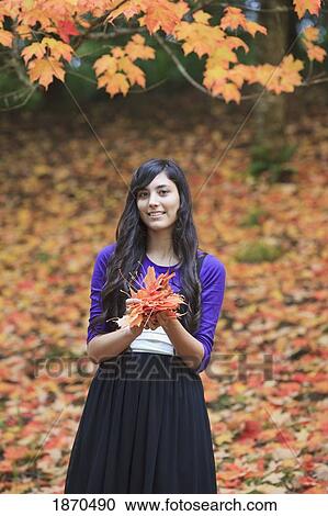 a teenage girl holding a pile of leaves in autumn View Large Photo Image Stock Image - a teenage girl holding a pile of leaves in autumn. Fotosearch