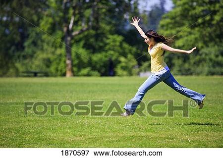 Stock Photo - a teenage girl leaping across the grass. Fotosearch