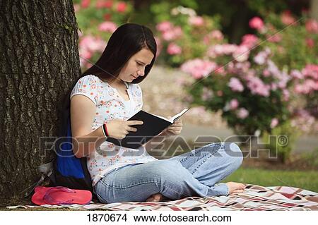 Picture - a teenage girl reading a book in the park. Fotosearch