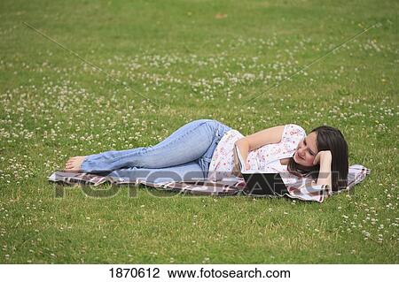 Stock Image - a teenage girl reading a book in the park. Fotosearch