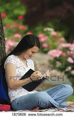 Stock Photograph - a teenage girl reading a book under a tree. Fotosearch