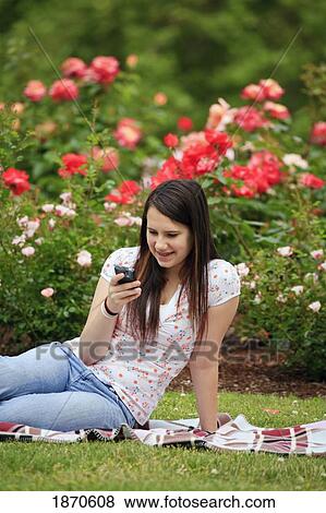 a teenage girl using her cellphone in a park View Large Photo Image Stock Photo - a teenage girl using her cellphone in a park. Fotosearch