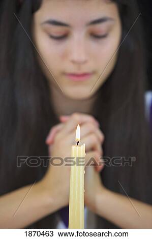 Stock Image - a teenage girl with hands clasped in prayer. Fotosearch