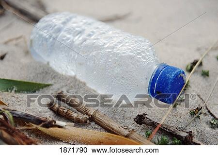 Stock Image - a water bottle left in the sand on the beach. Fotosearch