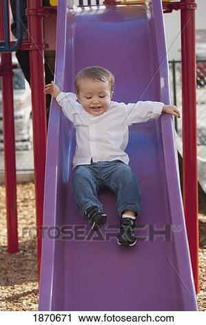 Stock Image - a young boy going down the slide. Fotosearch