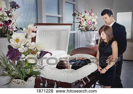 a young couple views a deceased loved one in a coffin View Large Photo Image Stock Photo - a young couple views a deceased loved one in a coffin. Fotosearch